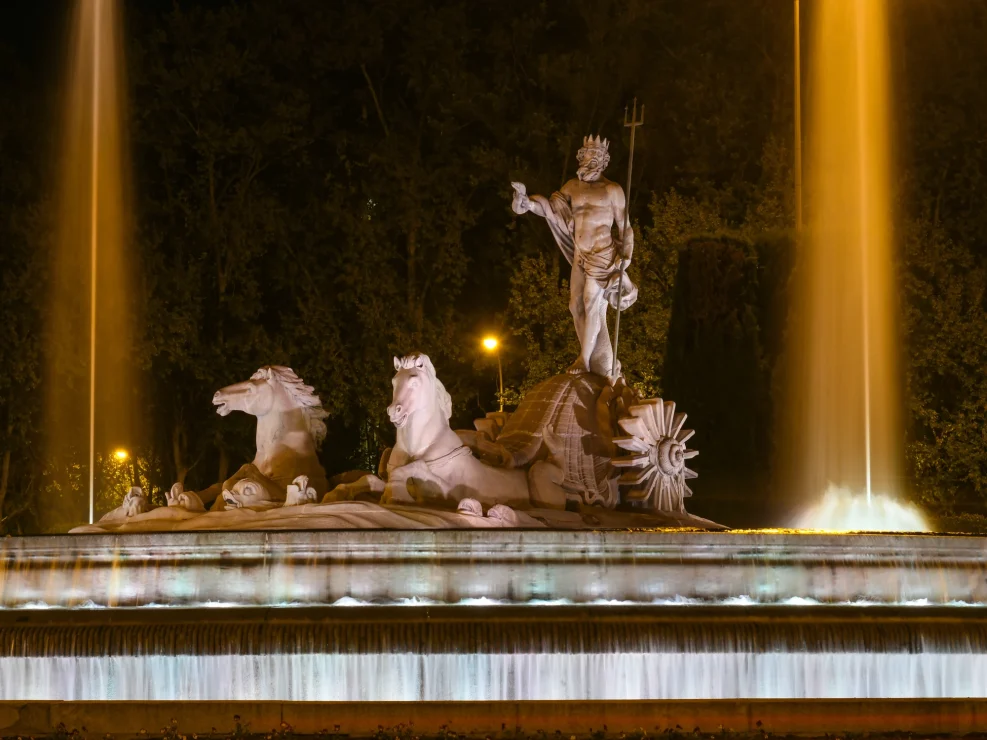 Fountain of Neptune in Madrid illuminated at night.