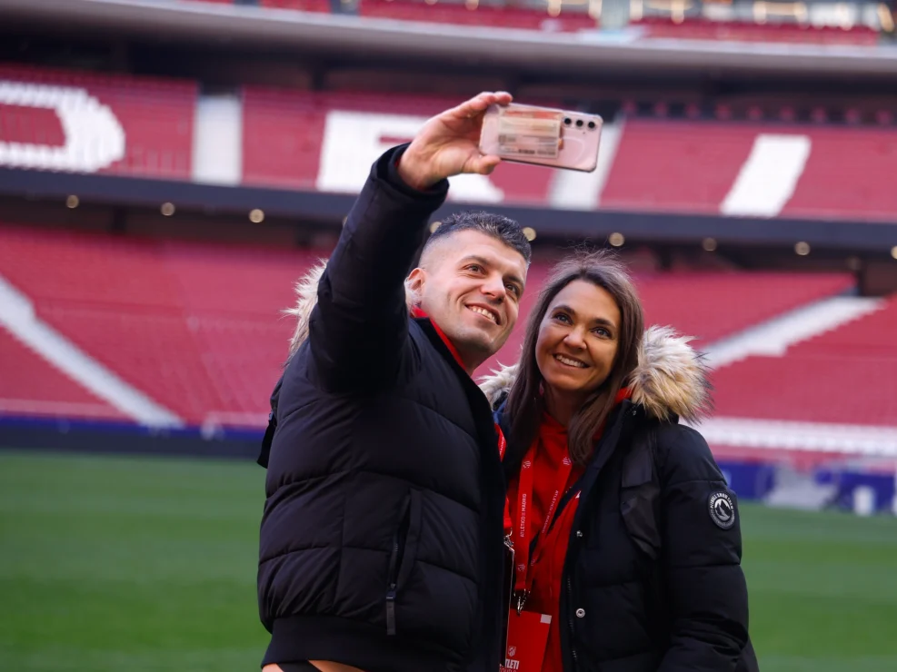 Two fans taking a selfie on the pitch at Atletico de Madrid stadium.