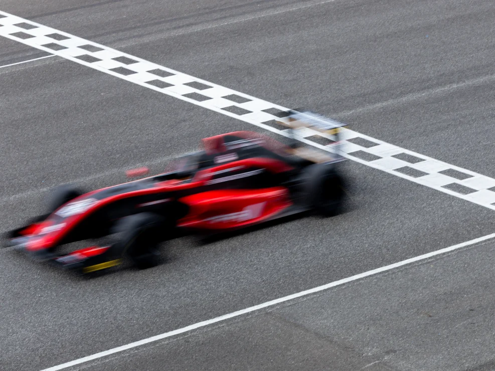 Blurred race car driving fast across finish line.